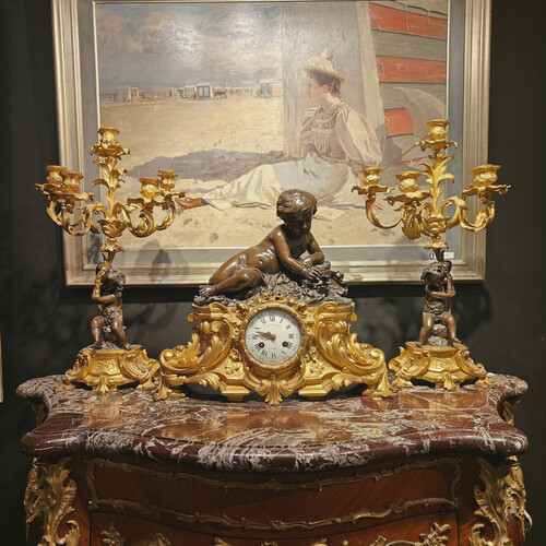 Belle garniture de cheminée trois pièces en bronze doré et patiné couronnée d'un enfant jouant avec un papillon. Travail Français du 19eme siècle   Cadran signé Raingo frères à Paris