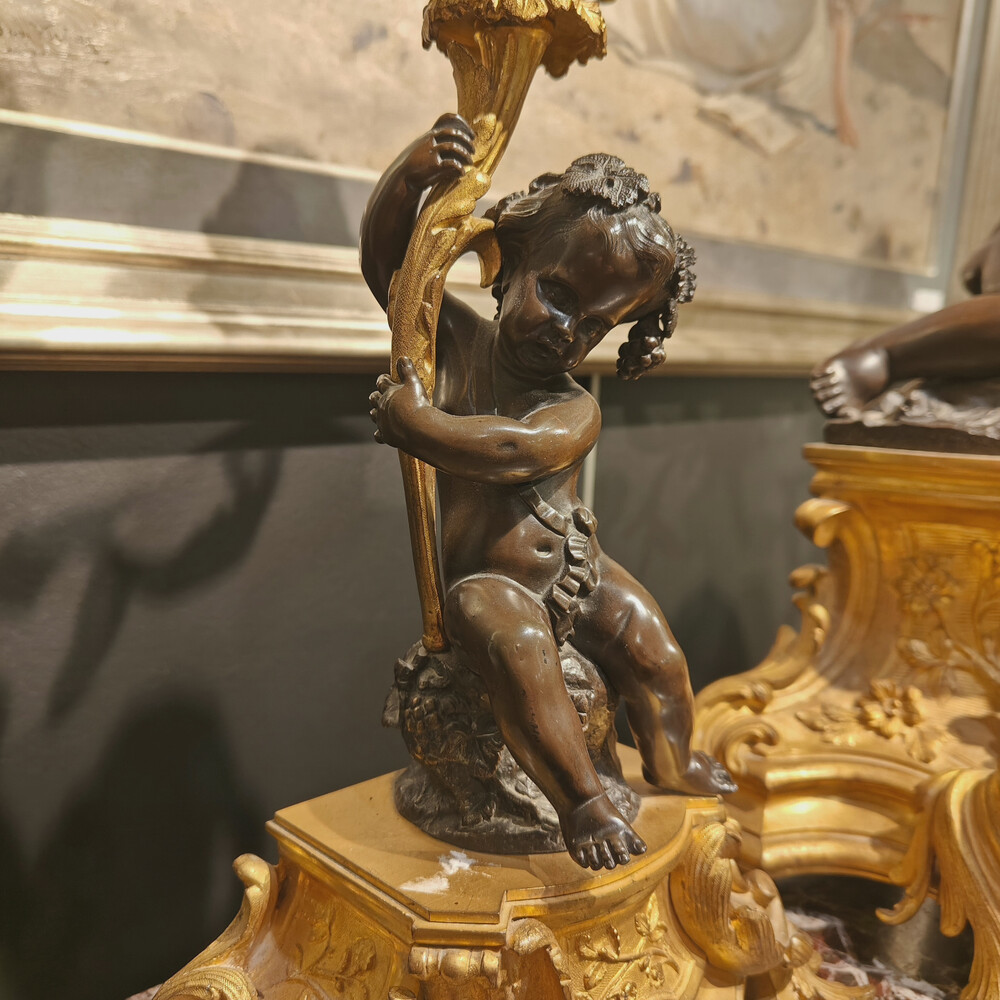 Belle garniture de cheminée trois pièces en bronze doré et patiné couronnée d'un enfant jouant avec un papillon. Travail Français du 19eme siècle   Cadran signé Raingo frères à Paris