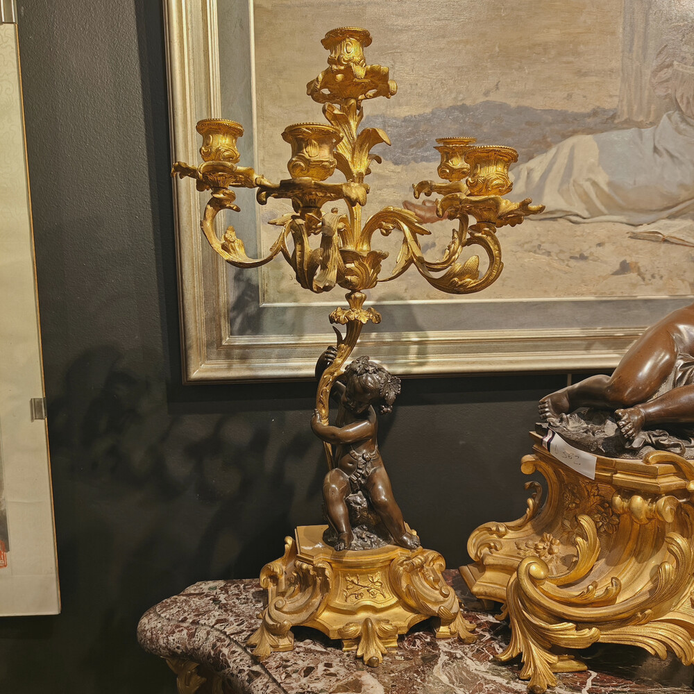 Belle garniture de cheminée trois pièces en bronze doré et patiné couronnée d'un enfant jouant avec un papillon. Travail Français du 19eme siècle   Cadran signé Raingo frères à Paris