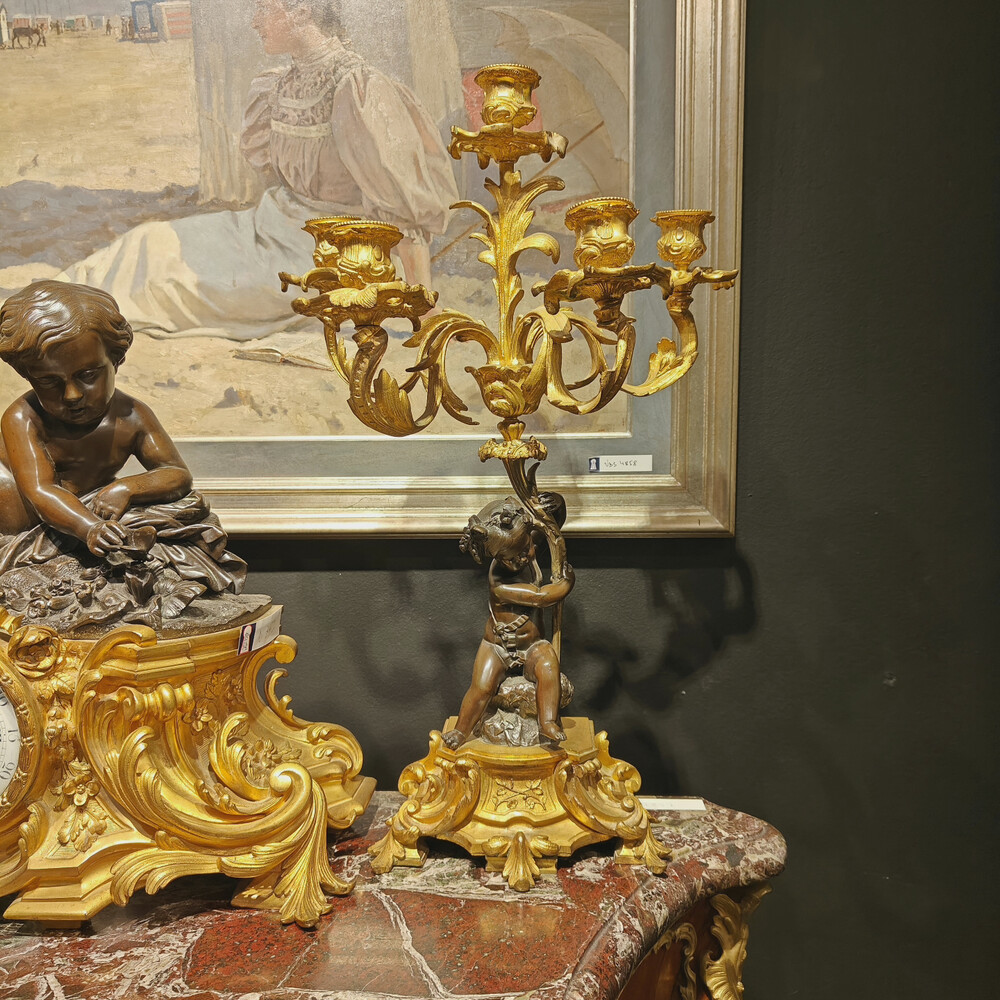 Belle garniture de cheminée trois pièces en bronze doré et patiné couronnée d'un enfant jouant avec un papillon. Travail Français du 19eme siècle   Cadran signé Raingo frères à Paris