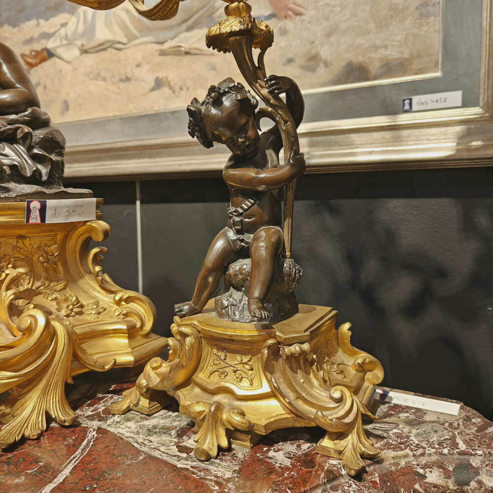 Belle garniture de cheminée trois pièces en bronze doré et patiné couronnée d'un enfant jouant avec un papillon. Travail Français du 19eme siècle   Cadran signé Raingo frères à Paris